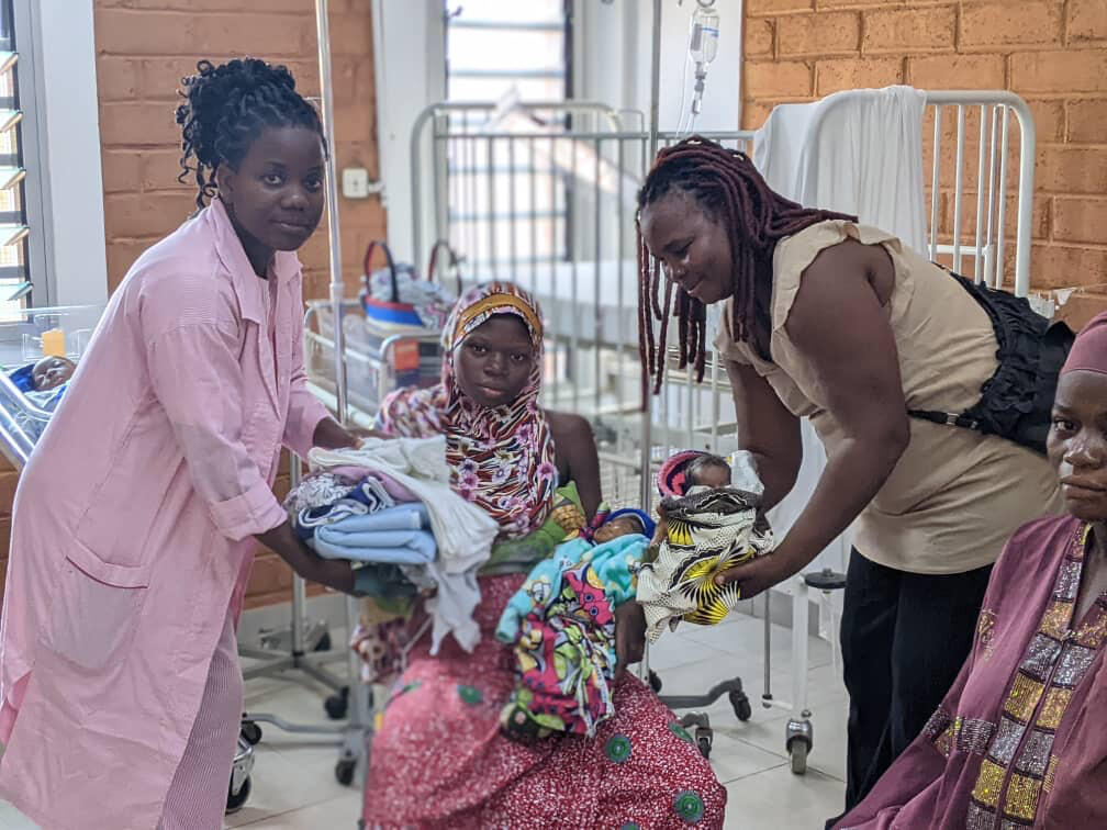 Drei Frauen in einer Frauenklinik mit einem frisch entbundenen Baby