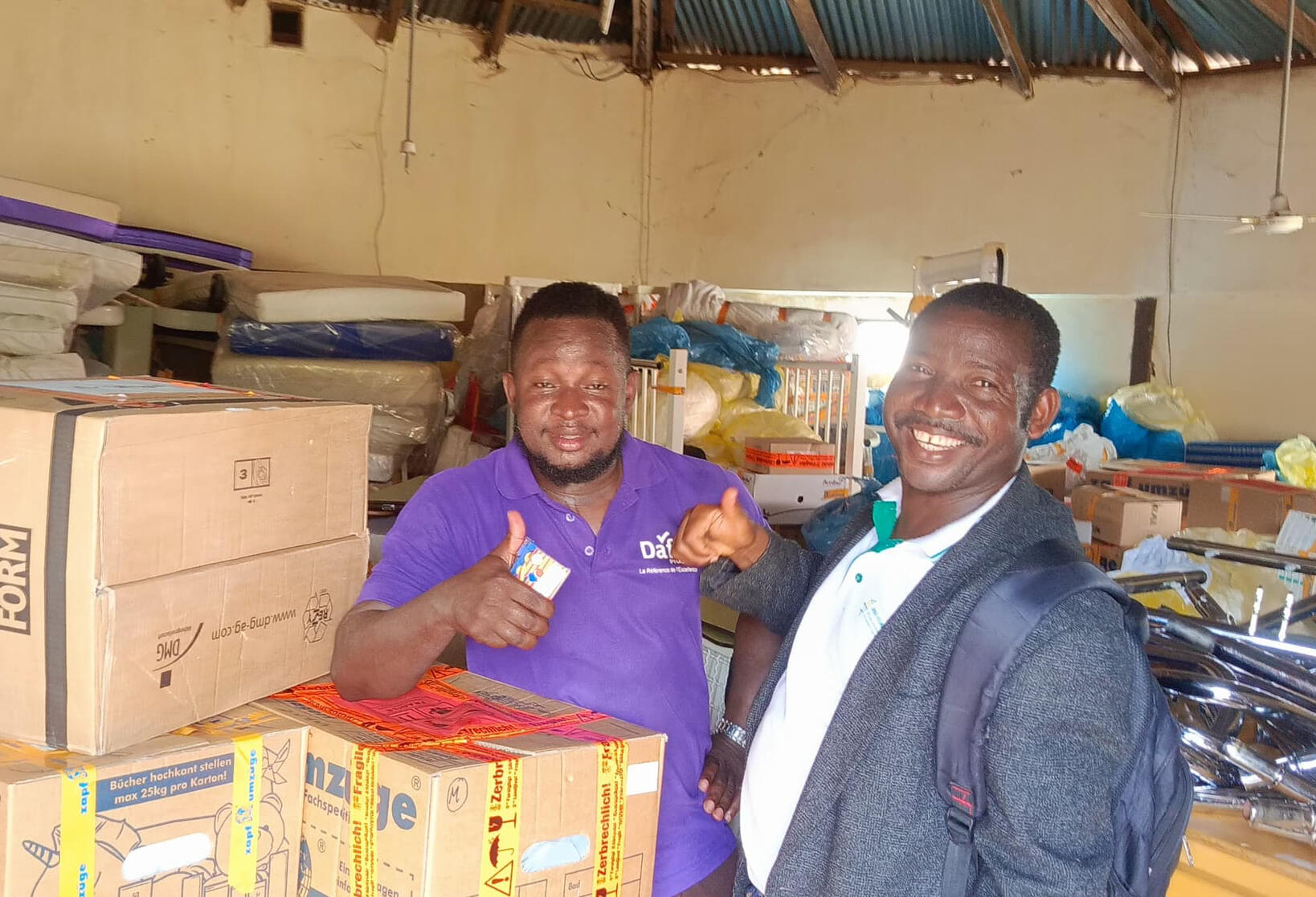 Zwei Personen vor einem Lager mit gelieferten Hilfsgütern.